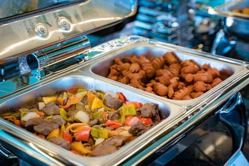 A buffet with two dishes: one with mixed vegetables and meat, and another with sausages. 2
