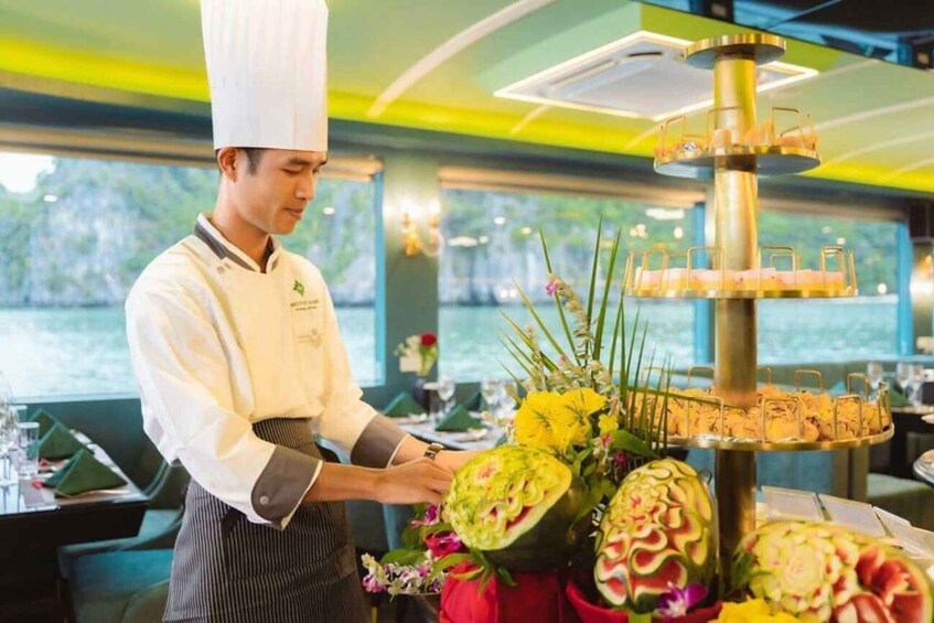 A chef arranging a decorative centerpiece with flowers and a tiered structure. 5