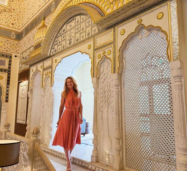 A woman in a red dress walking through an ornate doorway with intricate carvings and architectural details. 5