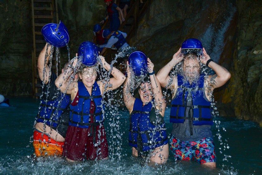 People in blue life vests and helmets being splashed with water. 3