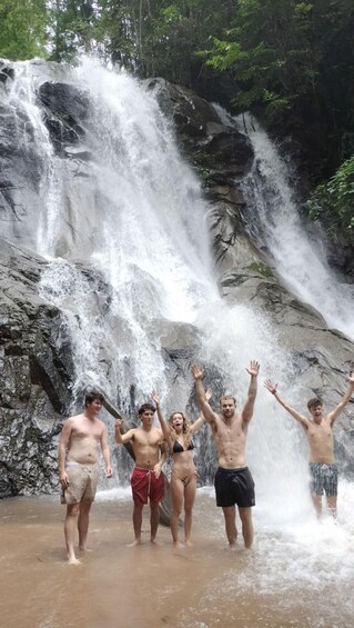 A group of people standing in front of a waterfall. 4