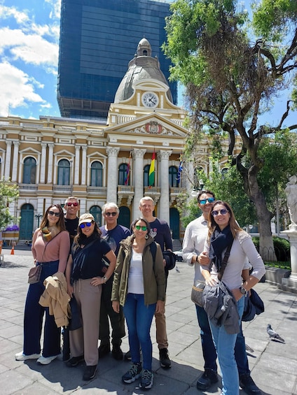 A group of people standing in front of a historic building with a clock tower and columns. 3