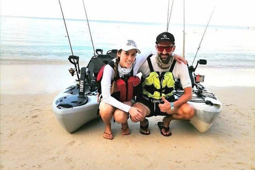 Dos personas sentadas en un bote sobre una playa arenosa, con cañas de pescar. 4
