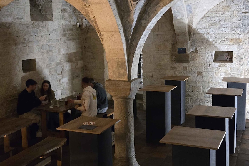An interior with stone arches, wooden tables, and benches. 4