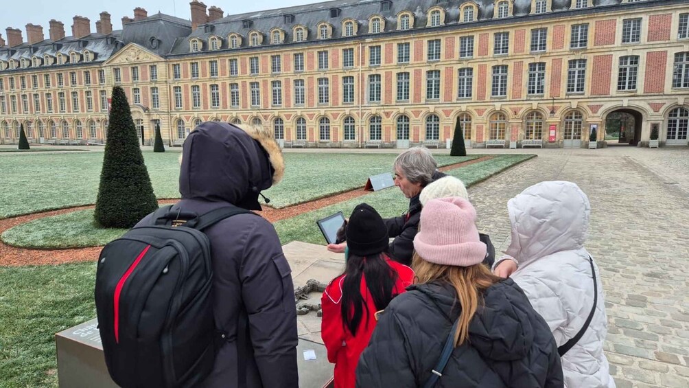 A group of people in a courtyard with a large historic building in the background. 3