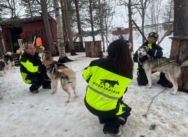 A group of people in a snowy outdoor setting, interacting with husky dogs. 5