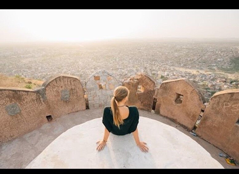 A person sitting on a large white platform overlooking a cityscape. 1