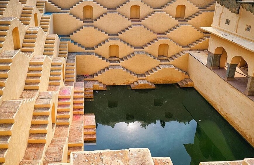 A series of terraced steps leading down to a reflective water body, surrounded by traditional architecture. 1