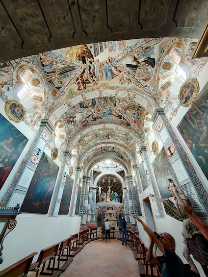 An ornate church interior with detailed frescoes and a central crucifix. 1