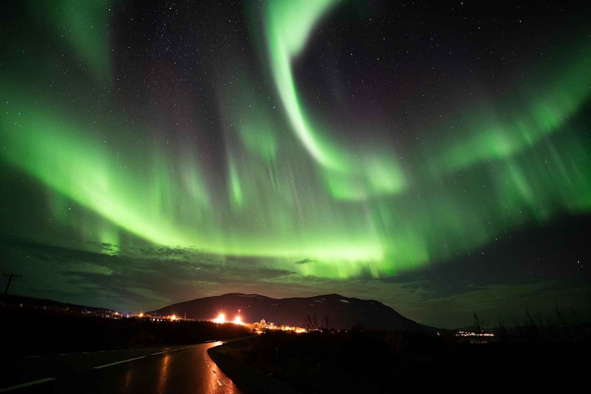 The Northern Lights over a road with a mountain in the background. 2