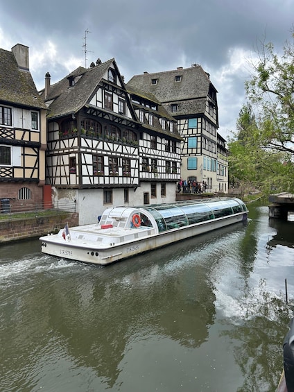 A narrowboat named STR.971F. on a river, passing by traditional timber-framed houses. 3