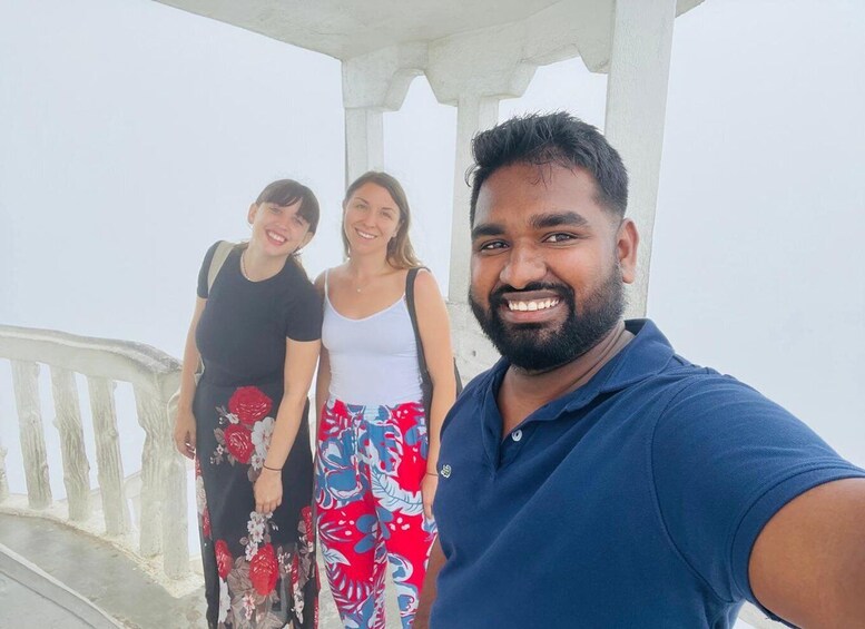 Three people standing on a bridge with a white railing, under a white structure. 2