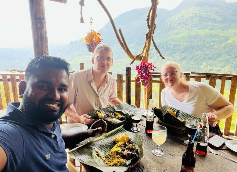 Three people dining outdoors with a scenic mountain view. 4