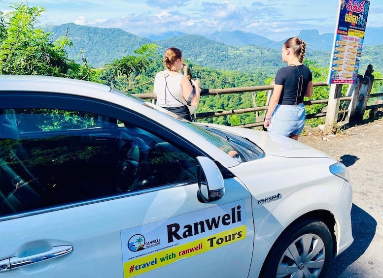 A white car with 'Ranwel Tours' branding parked at a scenic overlook. 1