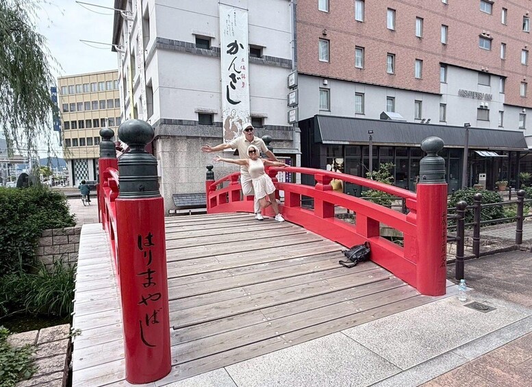 A red bridge with Japanese characters, a person in a white dress, and buildings in the background. 2