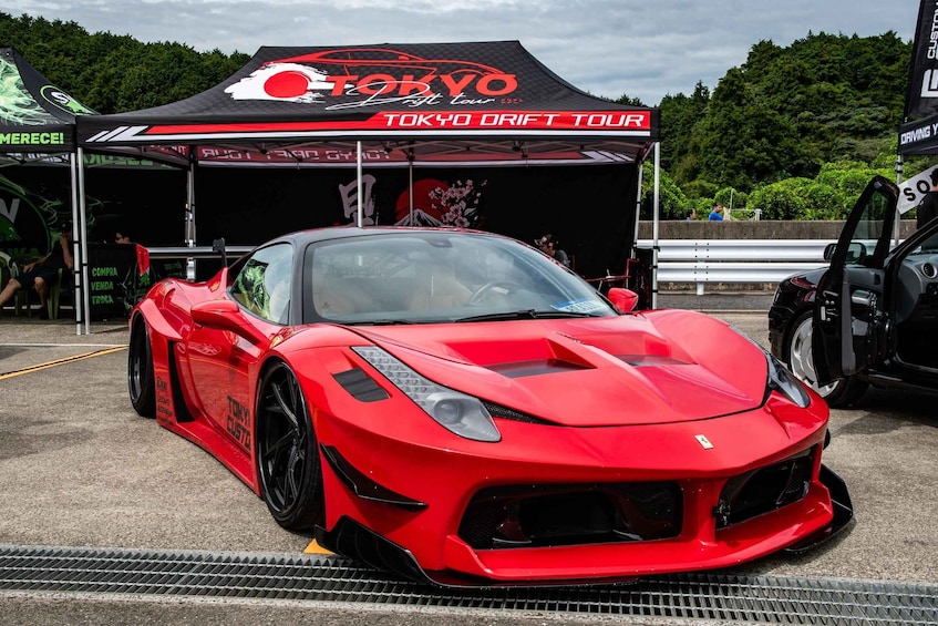 A red sports car parked under a Tokyo Drift Tour tent. 4