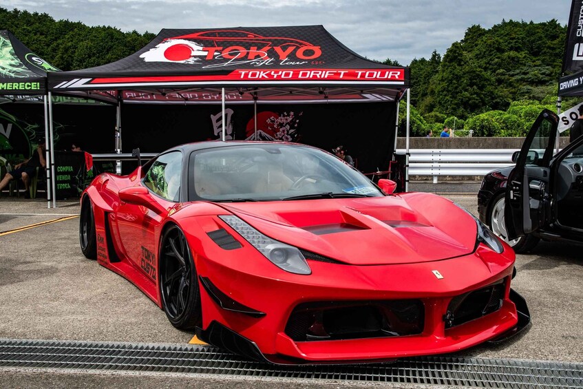 En rød sportsvogn parkeret under et Tokyo Drift Tour-telt. 2