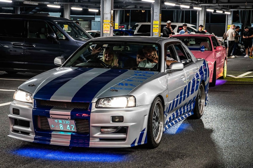 A modified sports car with blue and white stripes parked in a lot. 2