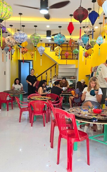 A vibrant restaurant interior with colorful lanterns, red plastic chairs, and a yellow wall. 4