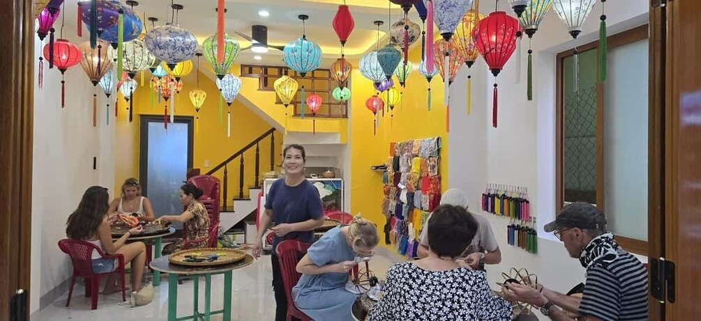 A group of people sitting around a table in a room decorated with colorful lanterns. 2