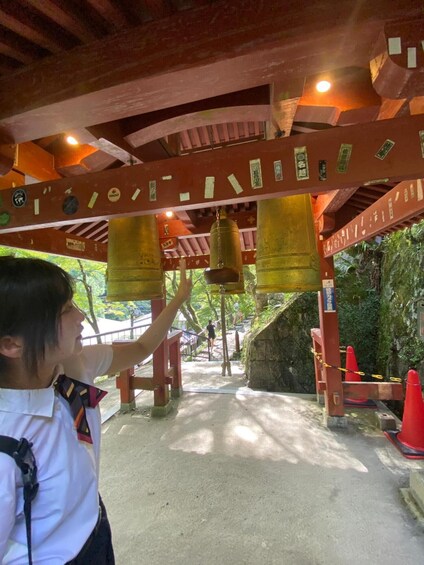A person at a temple with large bells and traditional architecture. 4