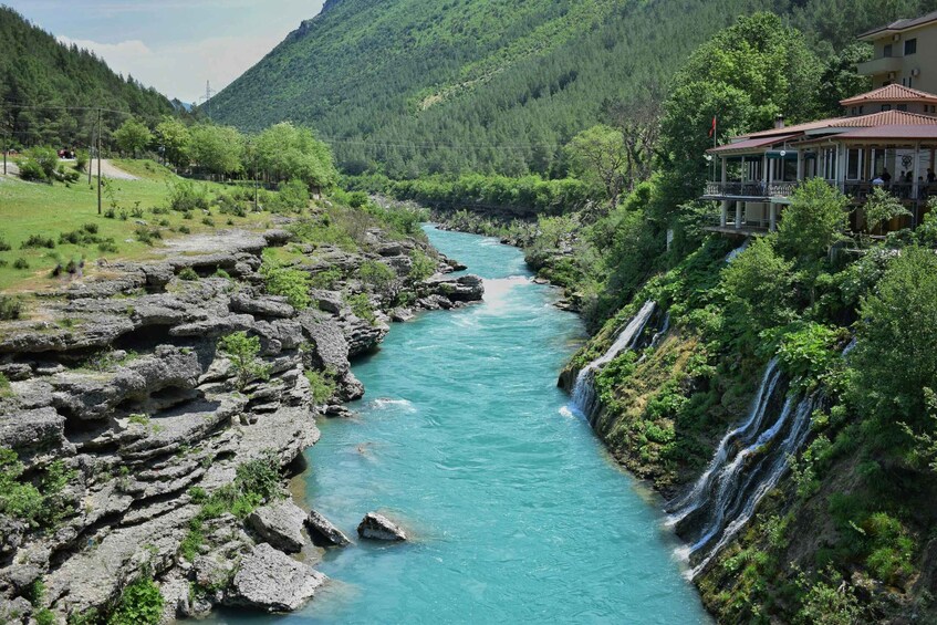 A river flowing through a mountainous area with a building on the right. 4