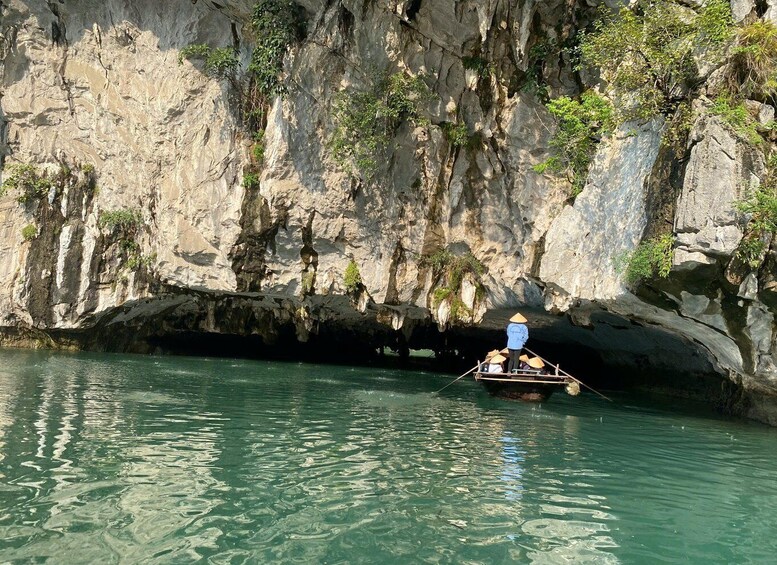 A person rowing a boat in a narrow waterway surrounded by rocky cliffs. 4