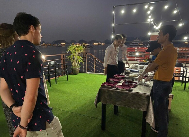A group of people standing around a table with food on a rooftop at night. 5