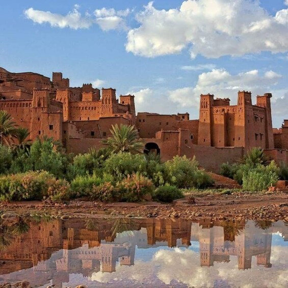 A historic fort with towers, palm trees, and a reflective water body. 1