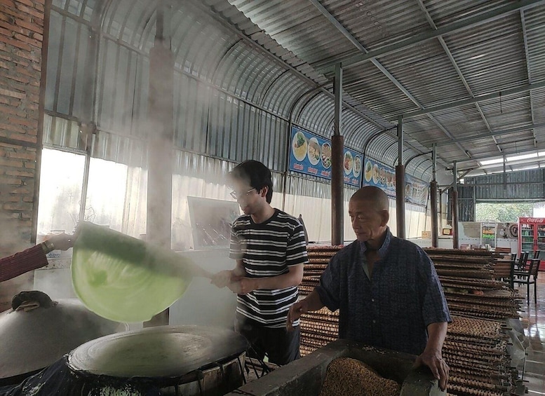 Two men cooking in a covered kitchen with a large pot and steam rising. 4