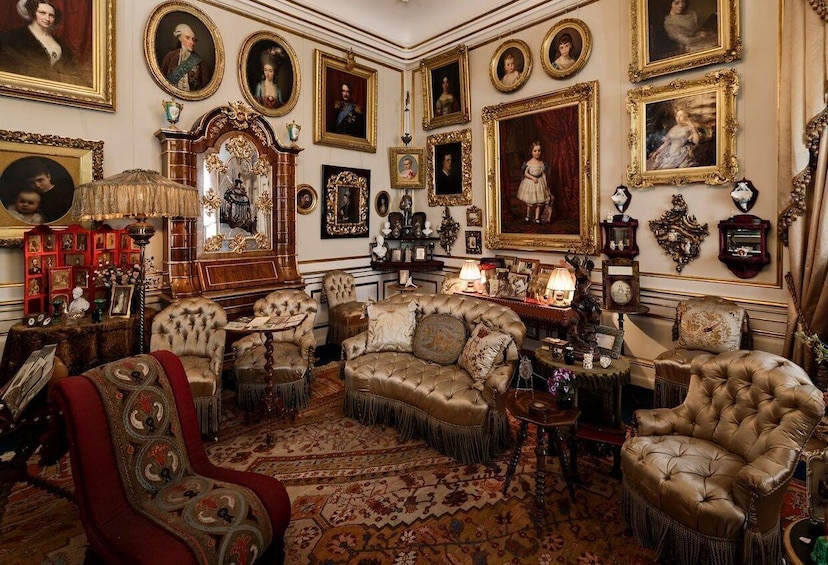 A richly decorated room with ornate furniture, framed portraits, and a large mirror. 5