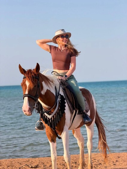 Eine Person reitet auf einem Pferd am Strand, im Hintergrund das Meer. 2