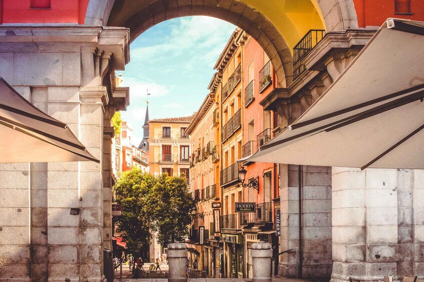 An archway framing a street with buildings, including a 'Hobby Filatelia' shop. 4