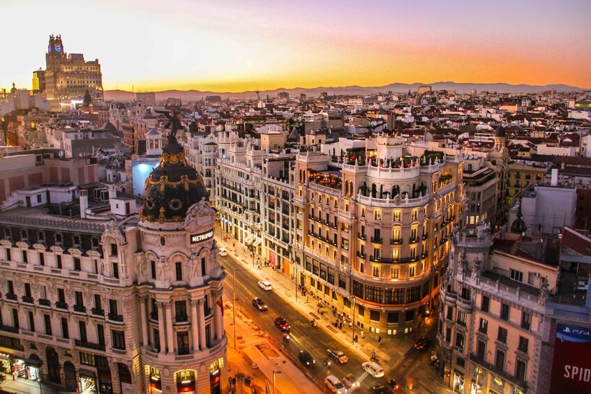 A cityscape at dusk with illuminated buildings and a prominent dome structure. 3