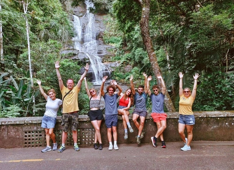 A group of people posing in front of a waterfall in a lush, green forest. 3