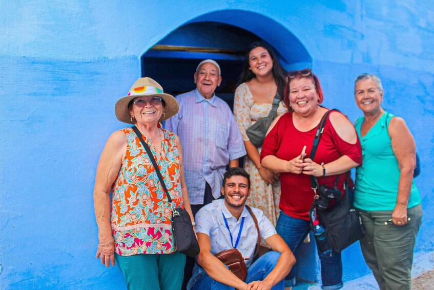 A group of people standing in front of a blue wall. 2