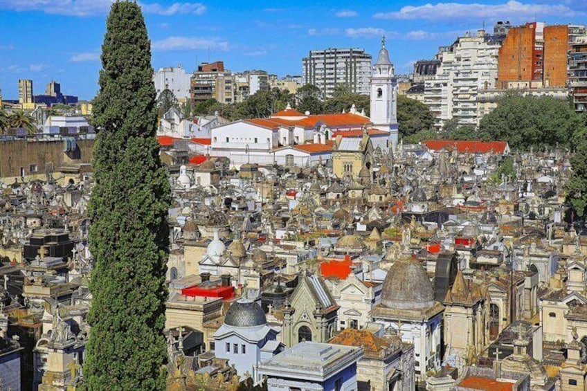 Un cimetière dense, où se trouvent de nombreux tombeaux et mausolées, entouré de bâtiments et dominé par une église imposante. 2