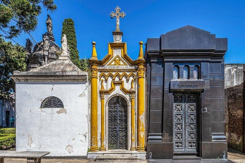 A white building with a cross on top, a yellow and white building with a door, and a black building with a sign. 3
