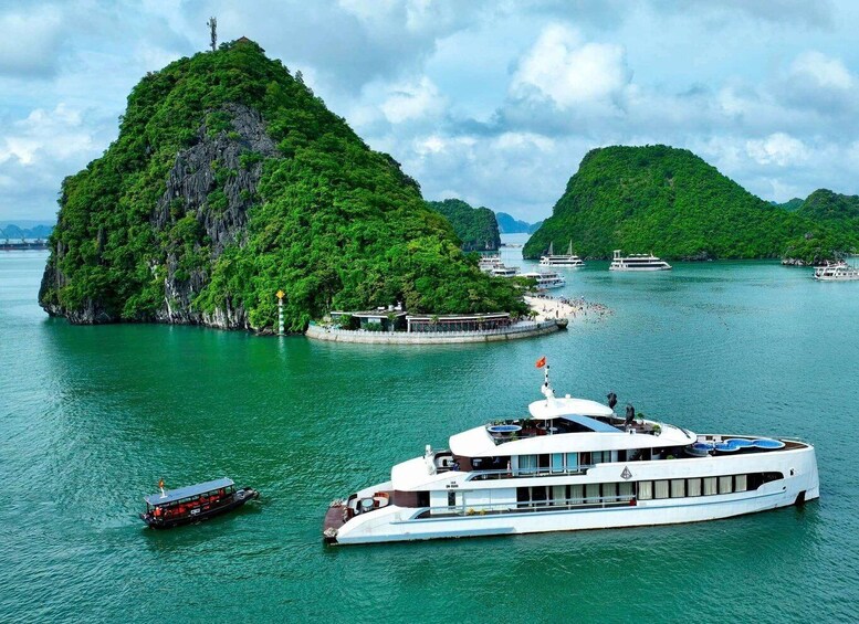 A large white boat docked near a lush green island with smaller islands in the background. 1