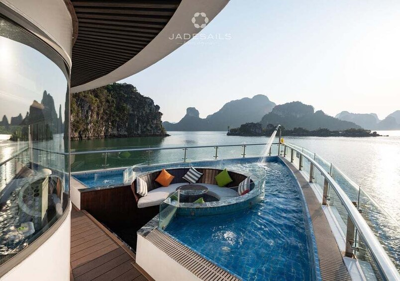 A luxurious pool area with a hot tub and seating on a cruise ship deck, overlooking a calm sea and rocky islands. 3