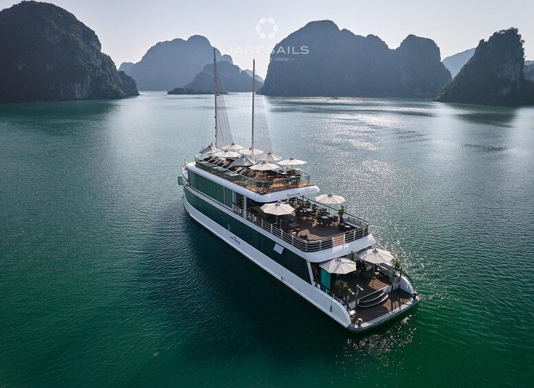A large white cruise ship with multiple decks and outdoor seating areas, sailing in a calm, turquoise sea with mountainous islands in the background. 2