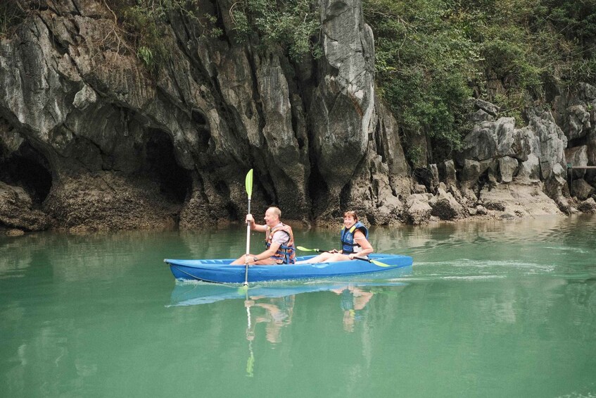 Due persone che fanno kayak su un fiume calmo, con ripide scogliere sullo sfondo. 4