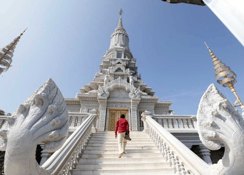 Una persona sube una escalera hacia un templo con esculturas ornamentales y una aguja puntiaguda. 1