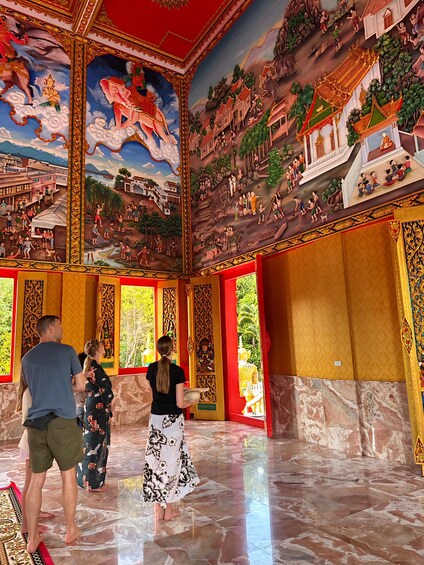 A temple interior with detailed murals, red and gold decorations, and a marble floor. 4