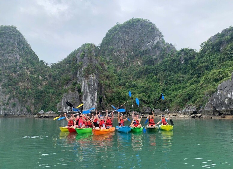 A group of people in colorful kayaks paddling on a calm river surrounded by lush green mountains. 1