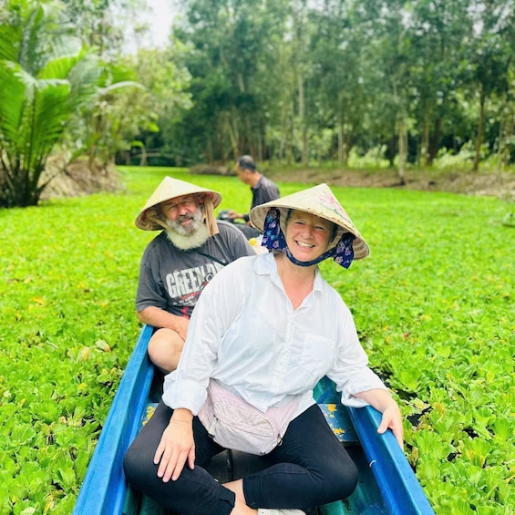 Two people in a boat on a green field with trees in the background. 5