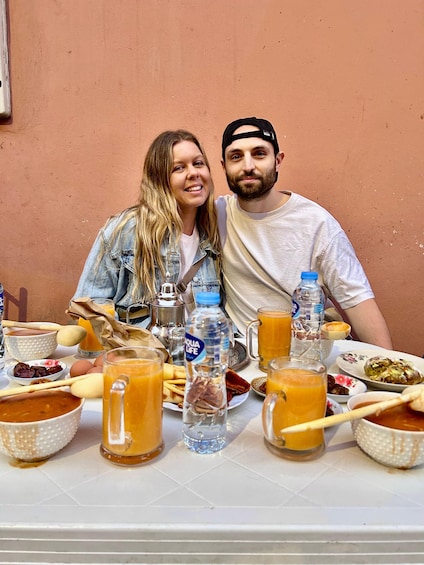 Two people seated at a table with food and drinks. 2