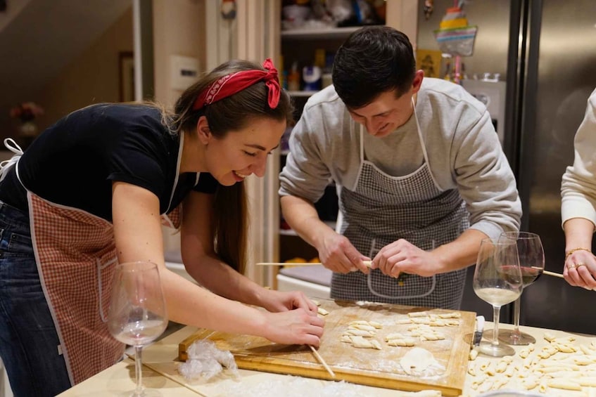Two people preparing food on a wooden board with dough and a rolling pin. 4