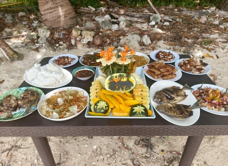 A variety of dishes on a table outdoors, with a tropical background. 3