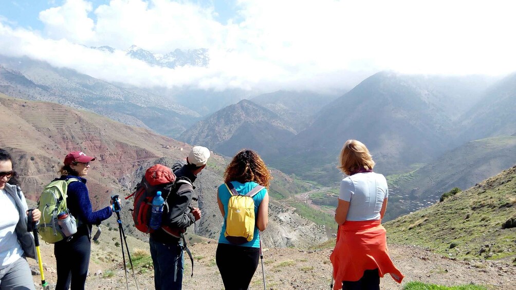 A group of hikers on a mountain trail with a valley and mountains in the background. 4